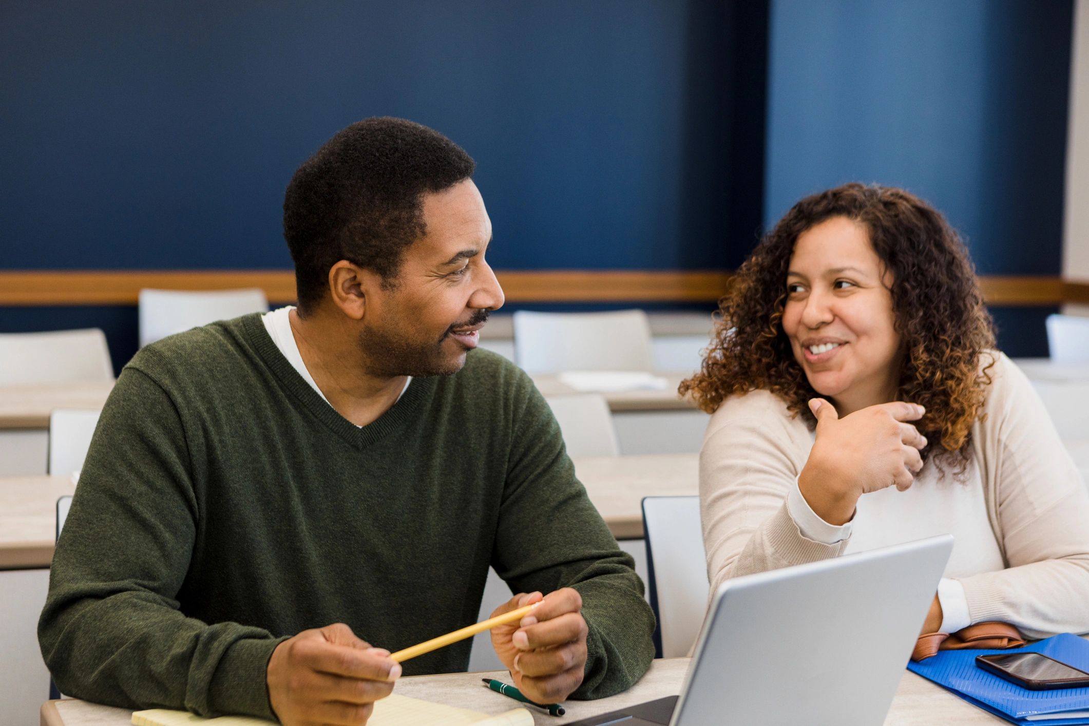Two adults studying together with a laptop and notebook