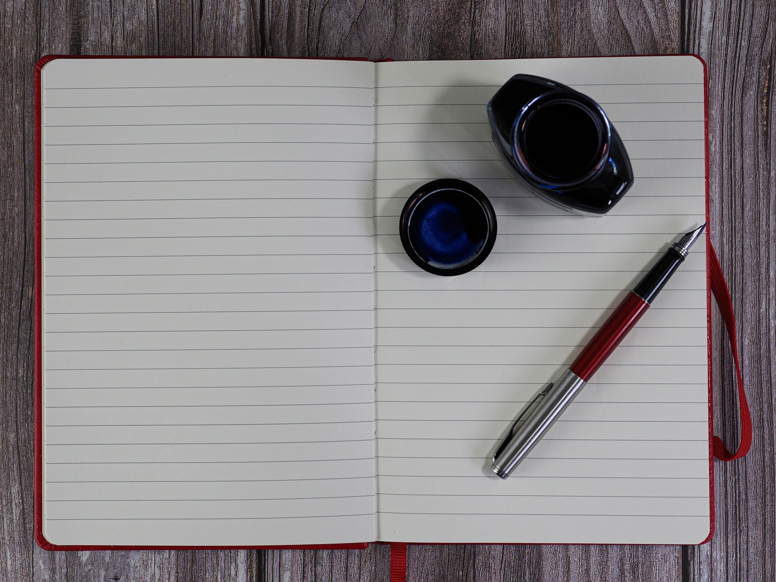 Notebook with pen and inkwell on a wooden desk