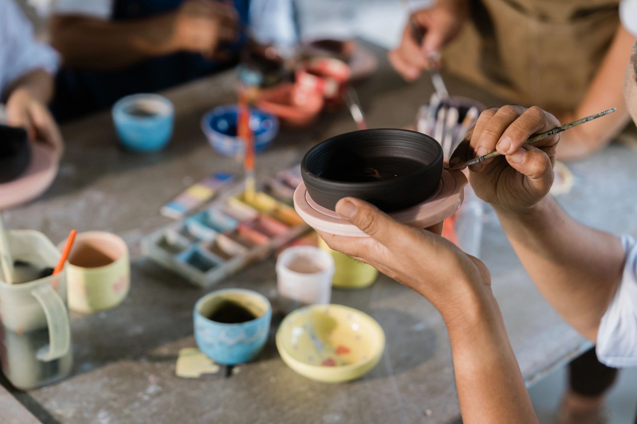 Hands painting pottery during an arts and crafts class