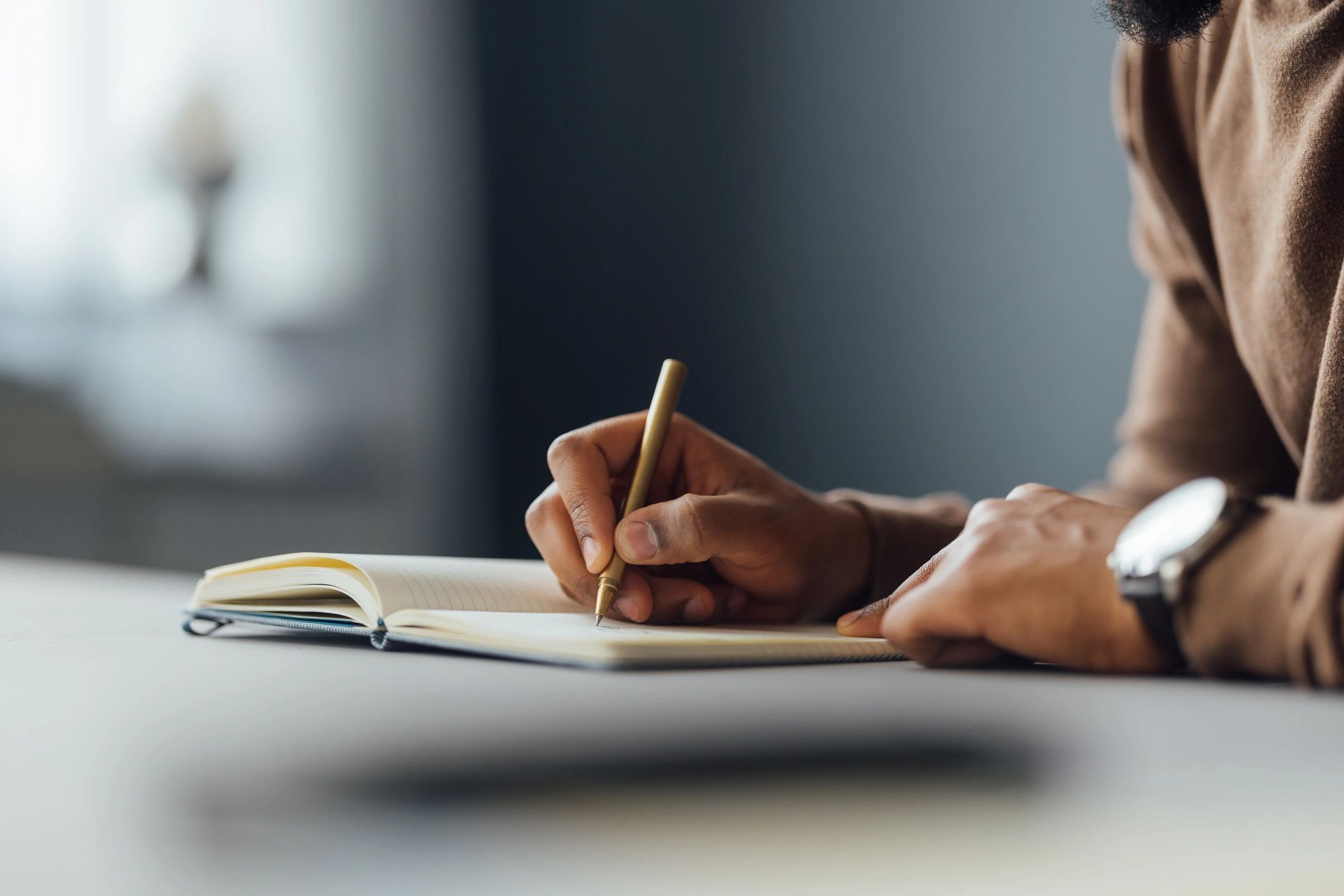 Hands writing in a notebook at a desk