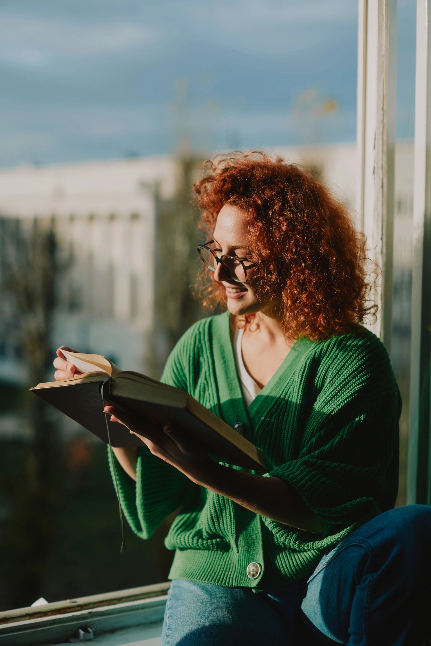 Person reading a book by a window